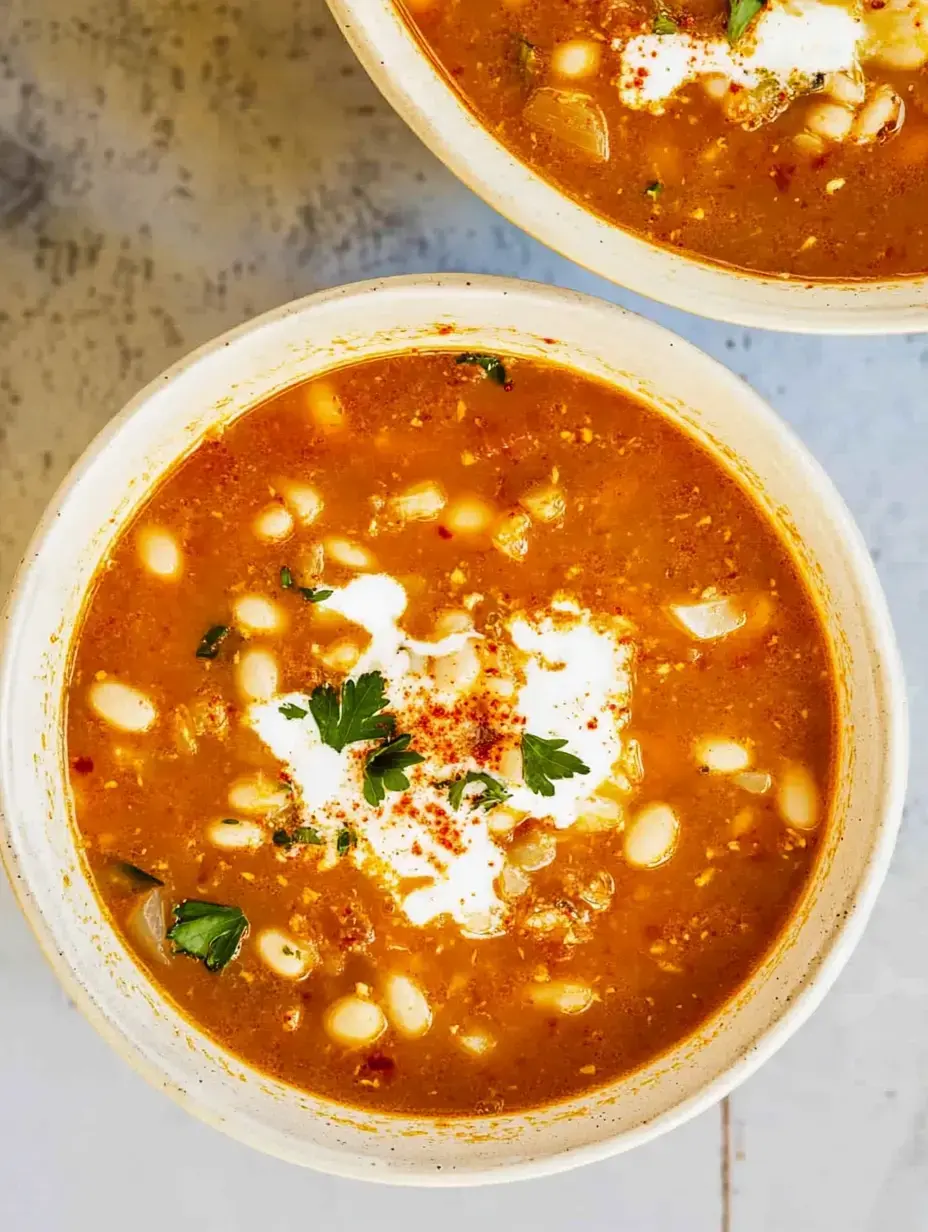 Vista detalhada de duas tigelas de sopa cobertas com natas, salsa e uma pitada de tempero.